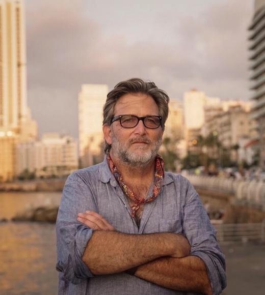 Man with arms crossed in front of blurred out buildings
