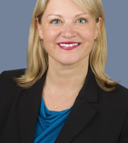Misty Humphries in front of a grey background wearing a black blazer