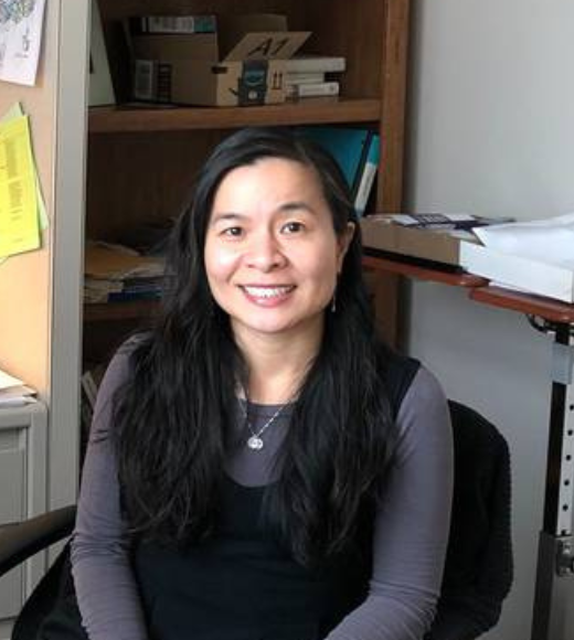 Woman sitting at a desk smiling in her office
