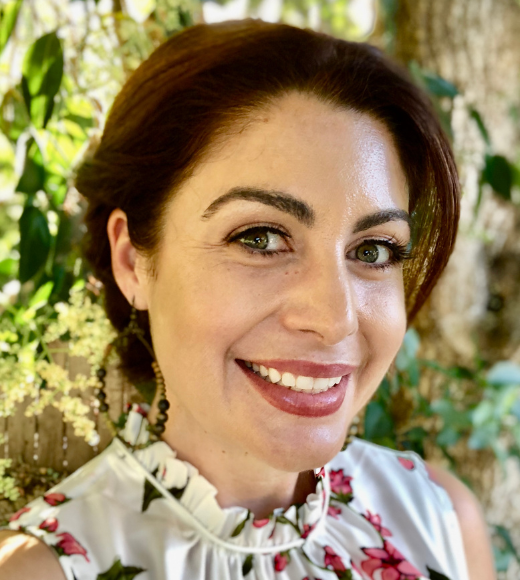 Close up photo of a woman wearing a floral blouse smiling outside