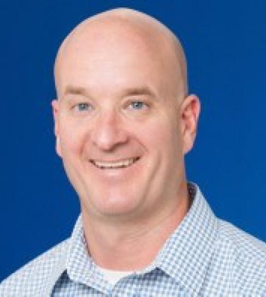 close up of a man smiling in front of a plain background