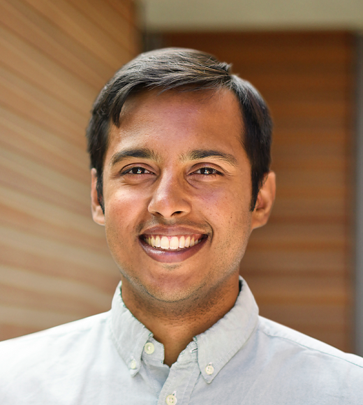 Close up headshot of a man wearing a button down shirt smiling.