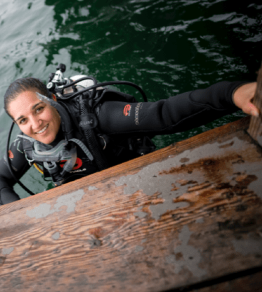 Woman smiling and wearing scuba diving gear in the water