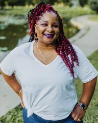an african american woman in a white t-shirt and jeans with a path and water in the background