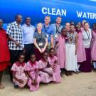 Group of people standing in front of a large truck that reads "clean water"