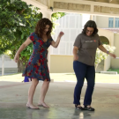 two women dancing with a courtyard behind them 