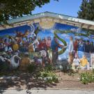 colorful mural on a side of a building that features different people together as a group with the words "la comunidad" and "a united community"