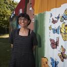 woman standing next to a butterfly mural
