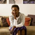 African America woman sitting on a couch looking into the camera with her head in her hand