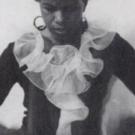 an African American woman in a black dress with a big white ruffle 
