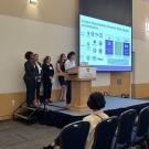 Group of EPM students at the stage doing a presentation for the Policy Symposium June 2023