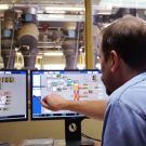 Image of plant operator at the central heating and cooling plant pointing at a computer monitor.