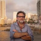 Man with arms crossed in front of blurred out buildings