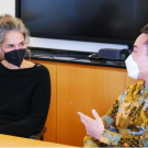 woman in a mask talking to a student inside a classroom