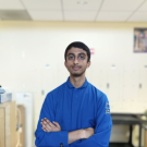 Young South Asian man in a blue lab coat inside a laboratory