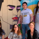 A group of people pose in front of a mural of Frida Kahlo