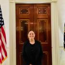 Woman standing in front of a door at the White House in between two flags