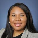 Professional headshot of woman wearing a gray suit jacket and black shirt