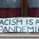 a sign that reads "racism is a pandemic"