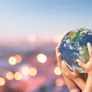 Hands holding up planet Earth.