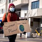 a man in a mask holding a sign that says support your local planet