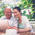 an Asian woman helps an older Asian an use the computer