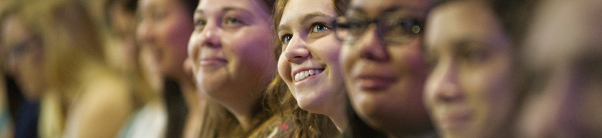 Students sitting in lecture close to one another smiling