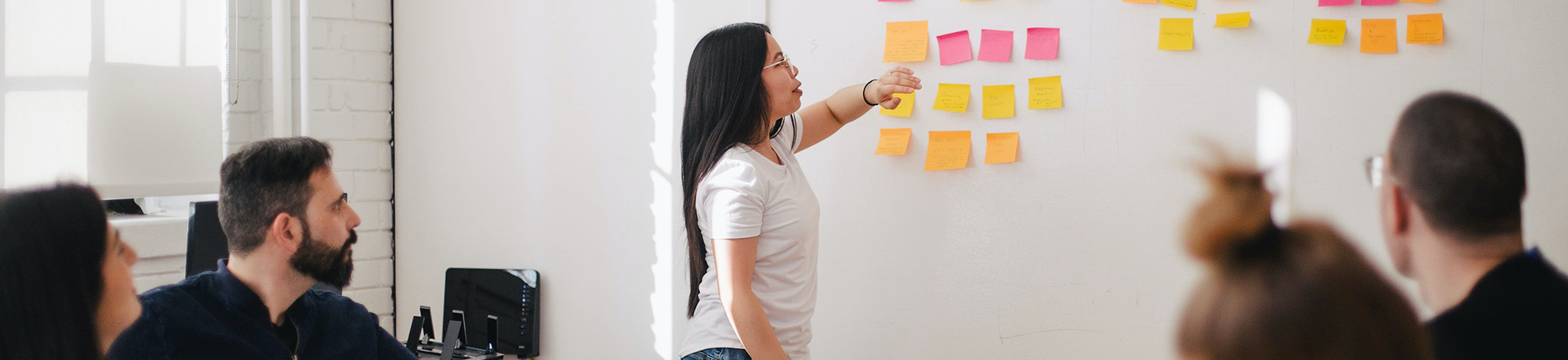 woman putting sticky notes on a white board