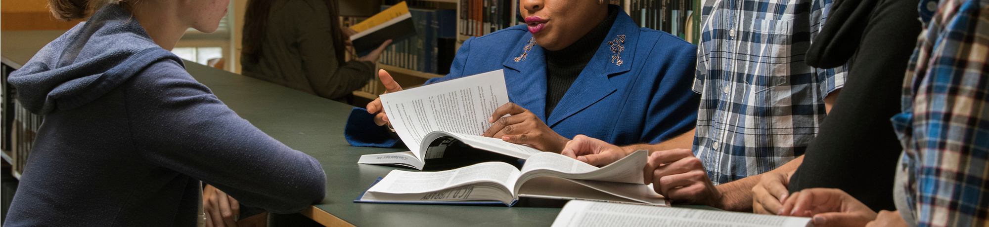 a woman turning the pages of the book in front of students